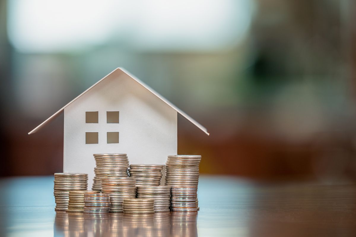 Model house beside stacks of coins, representing home equity and refinancing savings