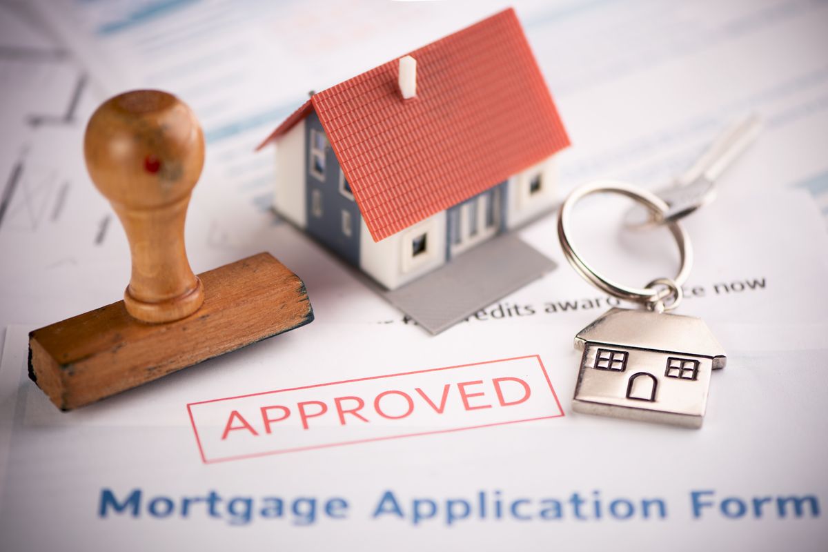 Approved mortgage application with house keys and a model home
